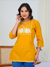 Woman wearing a mustard yellow kurta with white elephant design on a white background